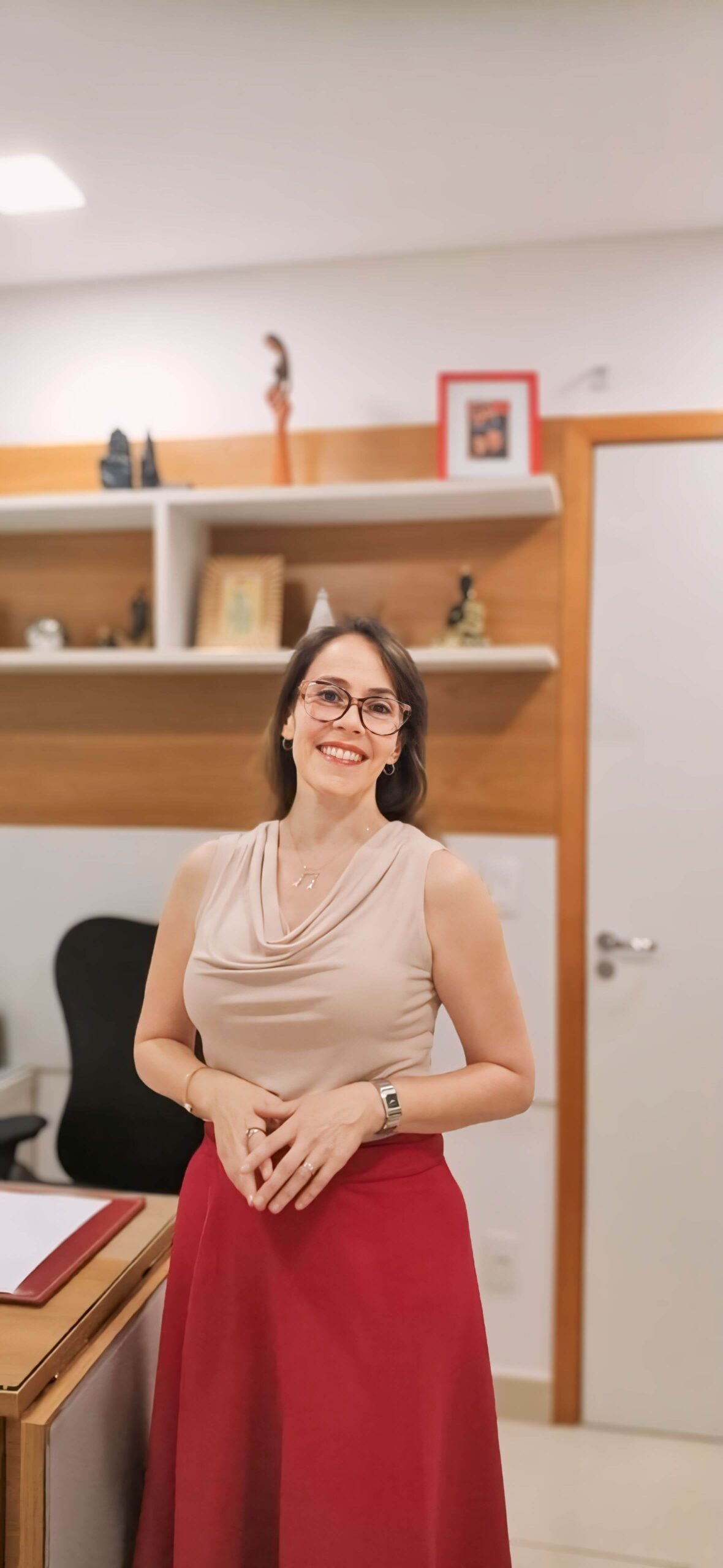 Dra. Aline Ambrósio, médica ginecologista, em pé em seu consultório